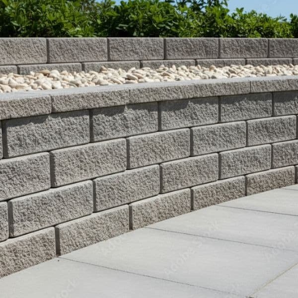 Structural retaining wall in stacked block with a paver cap